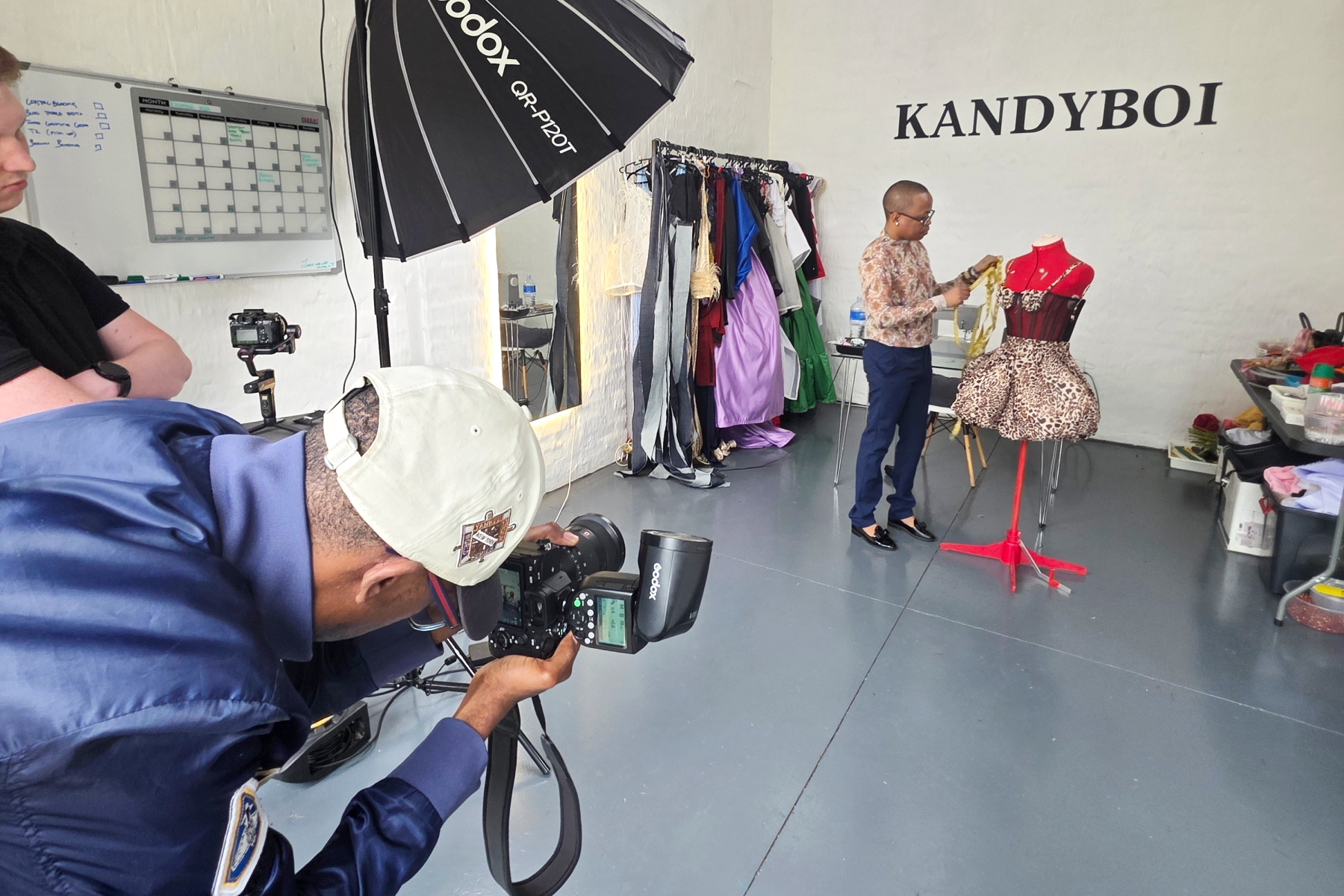 Behind the scenes videography shoot capturing fashion design studio with lighting and camera setup